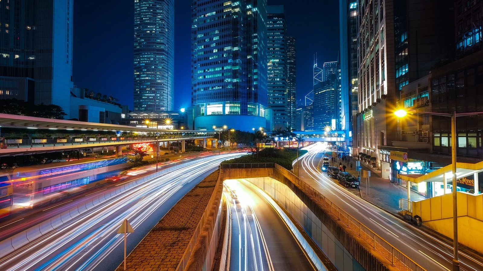 夜色中的城市天台，远处楼宇灯光连成一片暖色光带，一个人站在栏杆前低头看手机屏幕